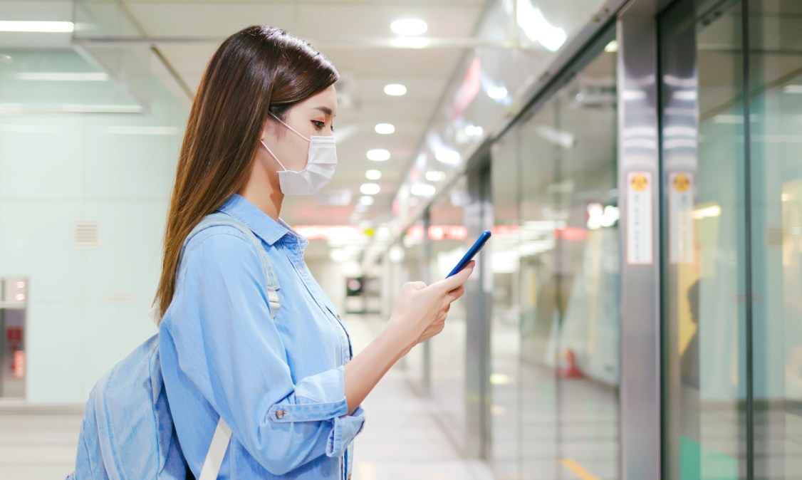 student wearing mask looking at smartphone