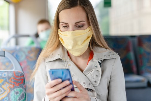 woman wearing mask using smartphone