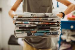 woman holding stack of newspapers